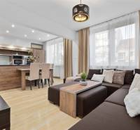 Living room with wood-patterned flooring in a 2-room apartment with a corner sofa and kitchen.