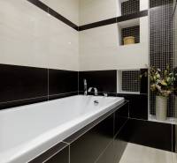 A bathroom with a bathtub and ceramic tiles in a black and white combination in a 2-room apartment.