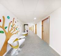 Office hallway with colorful wall decoration, chairs, and a closed box at the end.