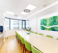 Offices with wood-patterned flooring, green chairs, a long table, refreshments in the corner.