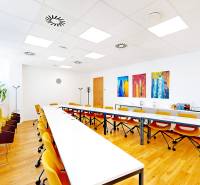 Interior of an office with wood-patterned flooring, yellow chairs, and modern art paintings.