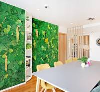 Offices with a vertical green wall, a desk and chairs, flooring with a wooden decor.