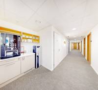 Office with a coffee machine and a water dispenser, bright walls and carpet.