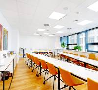 An office with white desks, orange chairs, and a wood-patterned floor.