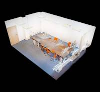 3D model of an office with a long desk setup and orange chairs, carpeted floor.