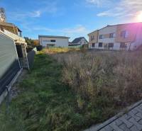 Plots - housing in Bytča with adjacent modern houses and a blue sky.