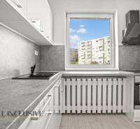 A kitchen in a 2-room apartment with a view and a wooden decor floor.