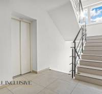 A staircase with light paneling and an elevator in a 2-room apartment.