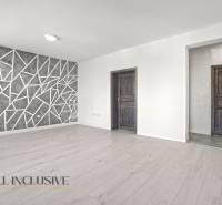 Living room with wood-patterned flooring and a geometric wall in a 2-room apartment.