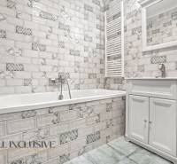 Bathroom in a 2-room apartment with white tiles and a bathtub.