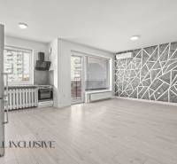 Kitchen and living room in a 2-room apartment with a wooden decor floor and a geometric wall.