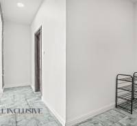 A hallway in a 2-room apartment with a wooden decor floor and a shoe rack.