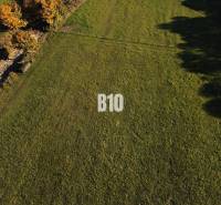 A grassy residential plot in Petrovice, surrounded by greenery and trees.