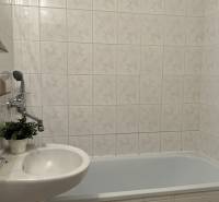 A bathroom with a bathtub and a sink in a 2-room apartment, tiled with tiles.
