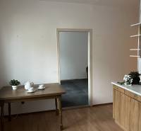 A kitchen in a 2-room apartment with a wooden decor floor, a table, and dishes.