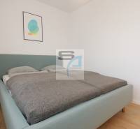 Bedroom with a bed and minimalist decoration in a 2-room apartment, floor with wooden decor.