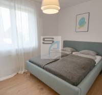 A bedroom with a large bed, curtains, and a wooden decor floor in a 2-room apartment.