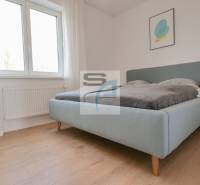 Bedroom in a 2-room apartment, light bed, wooden decor flooring, simple decor.