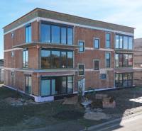 A new building on Dúhová Street in Slovenský Grob with glass walls and a parking lot.