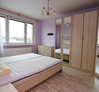 A bright bedroom with wood-patterned flooring in a 3-room apartment.