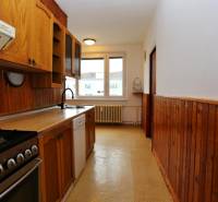 A kitchen in a 3-room apartment with wooden paneling and a gas stove.