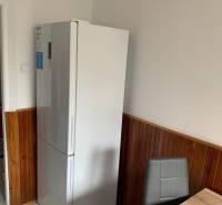 Kitchen in a 2-room apartment with a refrigerator, tiled walls, ceramic floor.