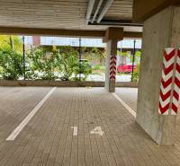 Inside a garage with parking spaces and marked pillars, floor with tiles.
