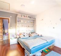 Children's room in a two-room apartment with a bed, shelves, and a wooden decor floor.
