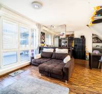 Living room with a comfortable sofa, wooden decor flooring, and large windows in a two-room apartment.