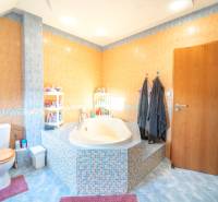 A bathroom with a corner bathtub and colorful tiles in a 2-room apartment.