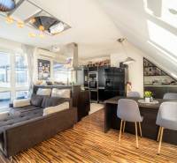 Living room with a kitchen in a 2-room apartment with a wooden decor floor and a comfortable sofa.