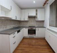 A kitchen in a 3-room apartment with white cabinets and a wood-patterned floor.