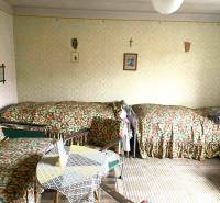 A room in a family house with three beds and a table, decorated with decor.
