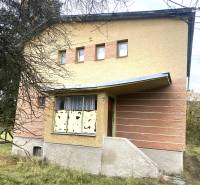 A family house in Rykynčice with colorful plaster, a sloped roof, and shutters.