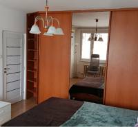 A bedroom in a one-room apartment with a large mirrored wardrobe and a chandelier.