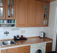A kitchen unit with cabinets and appliances in a studio apartment, floor with wood decor.