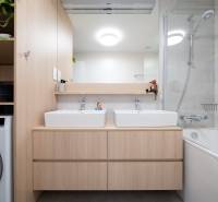 A bathroom in a 3-room apartment with two sinks, a mirror, and a bathtub.
