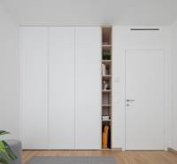 White built-in wardrobe with open shelves in a 3-room apartment with a wooden decor floor.