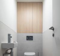 A bathroom with a ceramic sink, gray tiles, and a floor with a wood decor in a 3-room apartment.