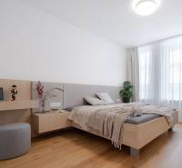 A bright bedroom in a three-room apartment with a wooden decor floor, plants by the window.