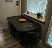 Dining area in a 3-room apartment with a wooden decor floor, with simple furnishings.