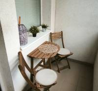 A balcony with wooden furniture and tiles in a 3-room apartment.