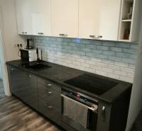A kitchen in a 3-room apartment with dark cabinets and a wooden-patterned floor.