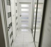 A hallway with mirrored closets and white doors in a 3-room apartment.