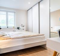 Bedroom in a 3-room apartment with wood-patterned flooring and white furniture.