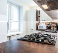 A kitchen in a 3-room apartment with white cabinets and a kitchen counter with brick cladding.