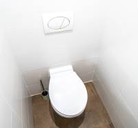 A toilet in a 3-room apartment with white tiles and a dark floor.