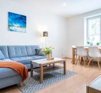 Living room in a three-room apartment with a sofa and a dining table, floor with wood decor.