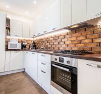 A kitchen in a 3-room apartment, with a brick wall and modern appliances.