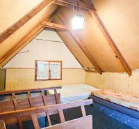 An attic room in a cottage with exposed beams and simple furniture.
